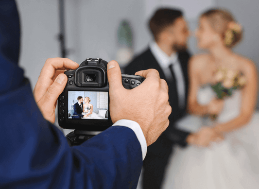 A photographer capturing a couple on their wedding day, reflecting The Ultimate Vegan Gentleman’s Wedding Wardrobe.